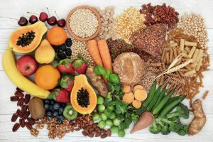 Food with high fiber content for a healthy diet with fruit, vegetables, whole wheat bread, pasta, nuts, legumes, grains, and cereals. High in antioxidants, anthocyanins, vitamins, and omega 3 fatty acid. Rustic background top view.